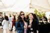 Two people at an event holding wine glasses and smiling at the camera